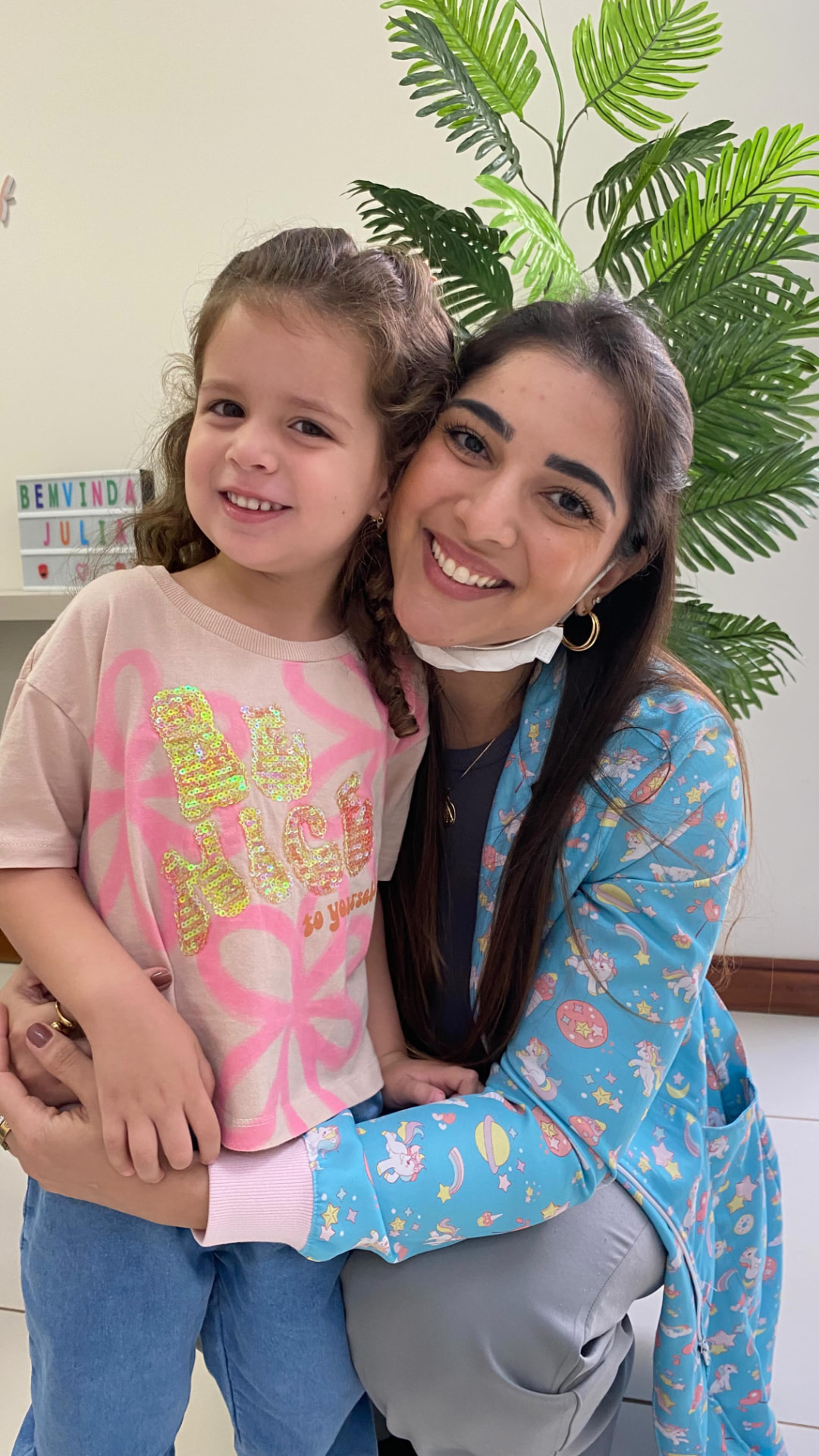 Dra. Bárbara Maluf abraçando uma pequena paciente na clínica